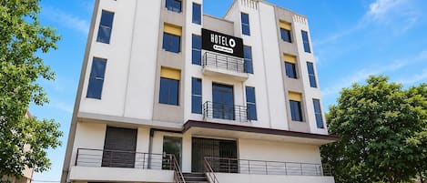 A multi-story hotel with a prominent sign, a staircase, and a gated entrance.