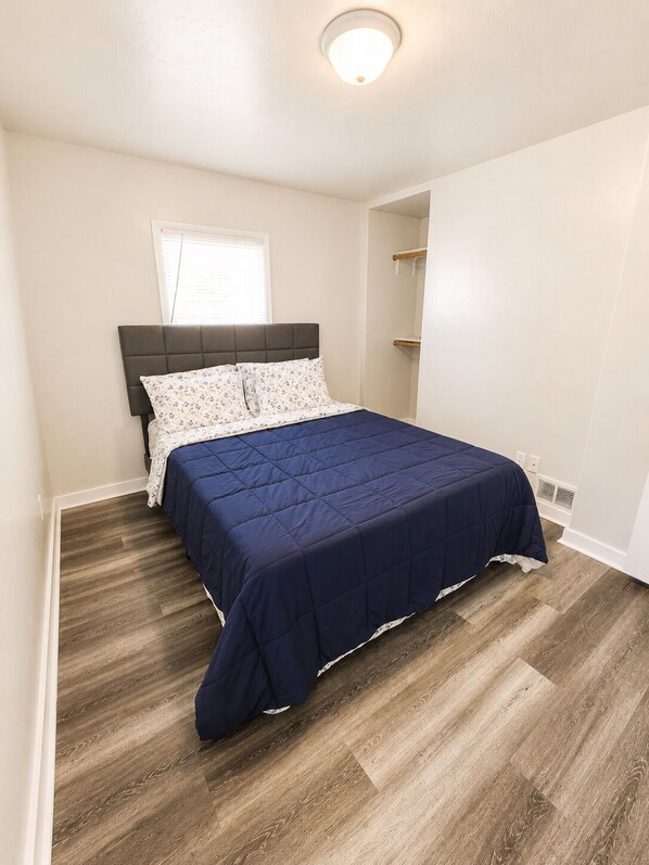 Een slaapkamer met een bed, een raam en een plafondlamp.