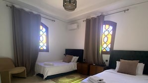 Une chambre d’hôtel avec deux lits, une chaise et un plafond décoratif.
