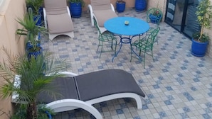 Une terrasse avec une table et des chaises, un canapé et des plantes en pot.