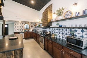 A kitchen with a central island, wooden cabinets, a microwave, and a patterned backsplash.