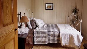 A bedroom with a bed, a bedside table with a lamp, a dresser, and a picture on the wall. - Comforter and garden #281772 Au rythme d'avant... (Berthier-sur-Mer)