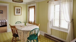 A dining room with a table set for two, a hanging light fixture, and a window with curtains. - Comforter and garden #281772 Au rythme d'avant... (Berthier-sur-Mer)