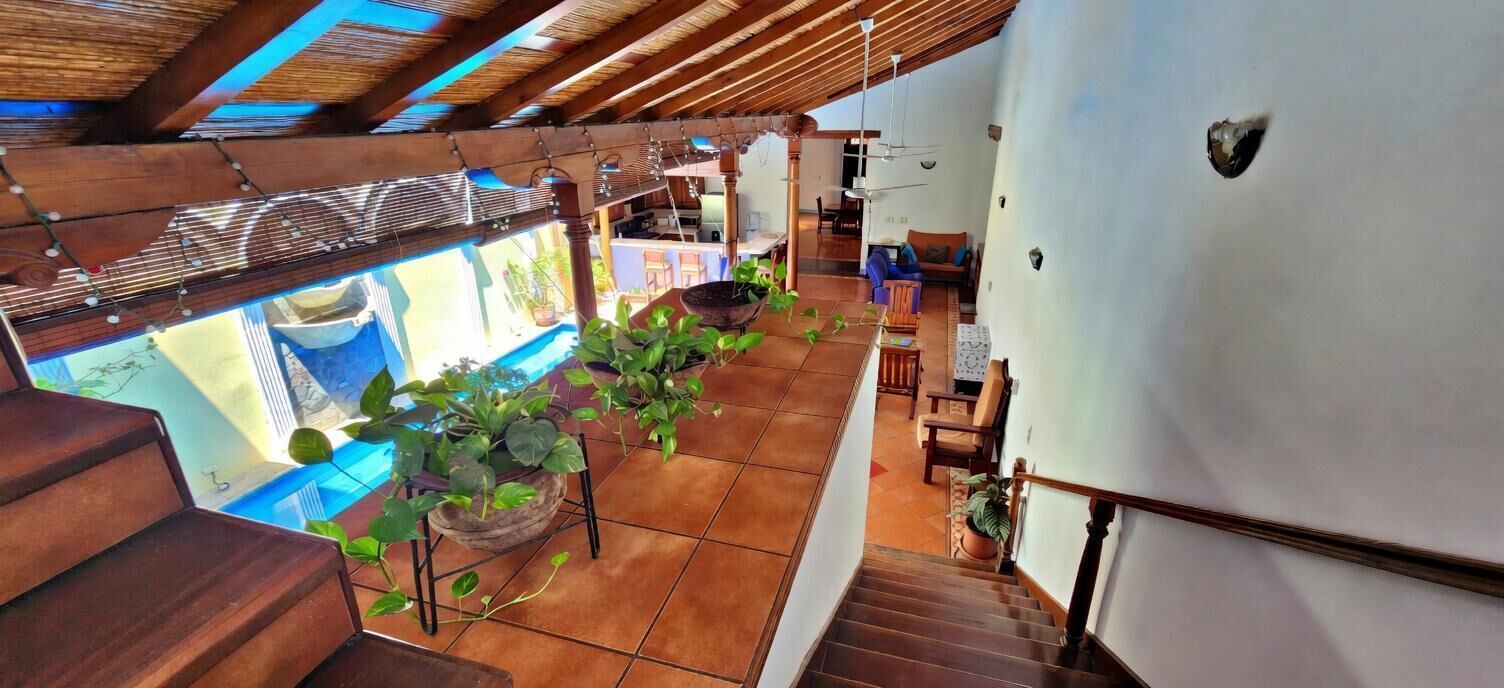 A spacious interior with a wooden staircase, a dining area, and a view of a swimming pool.