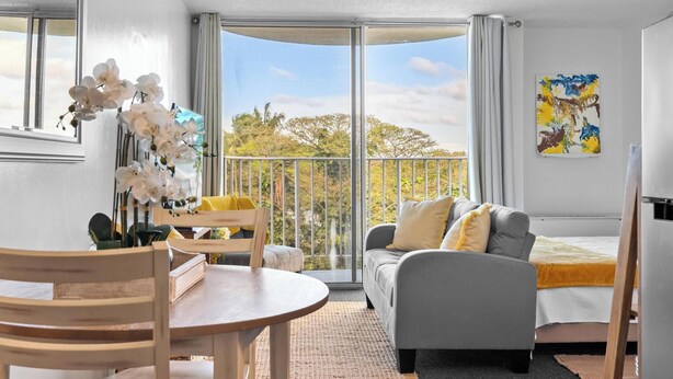 Et moderne værelse med balkon, spisebord, sofa og et maleri.