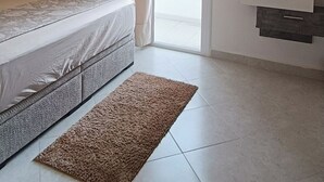 Ein Schlafzimmer mit einem Bett, einer Deckenleuchte, einer Schiebeglastür und einer eingebauten TV-Konsole.