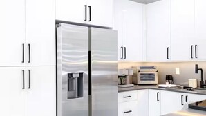 Una cucina moderna con mobili bianchi, un frigorifero in acciaio inossidabile e un forno integrato.