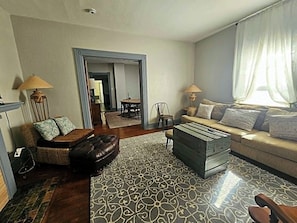 A living room with a sofa, armchair, ottoman, and a patterned rug.