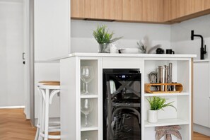 Eine moderne Küche mit weißen Schränken, einem eingebauten Kühlschrank und einem Holzregal mit Küchenutensilien.