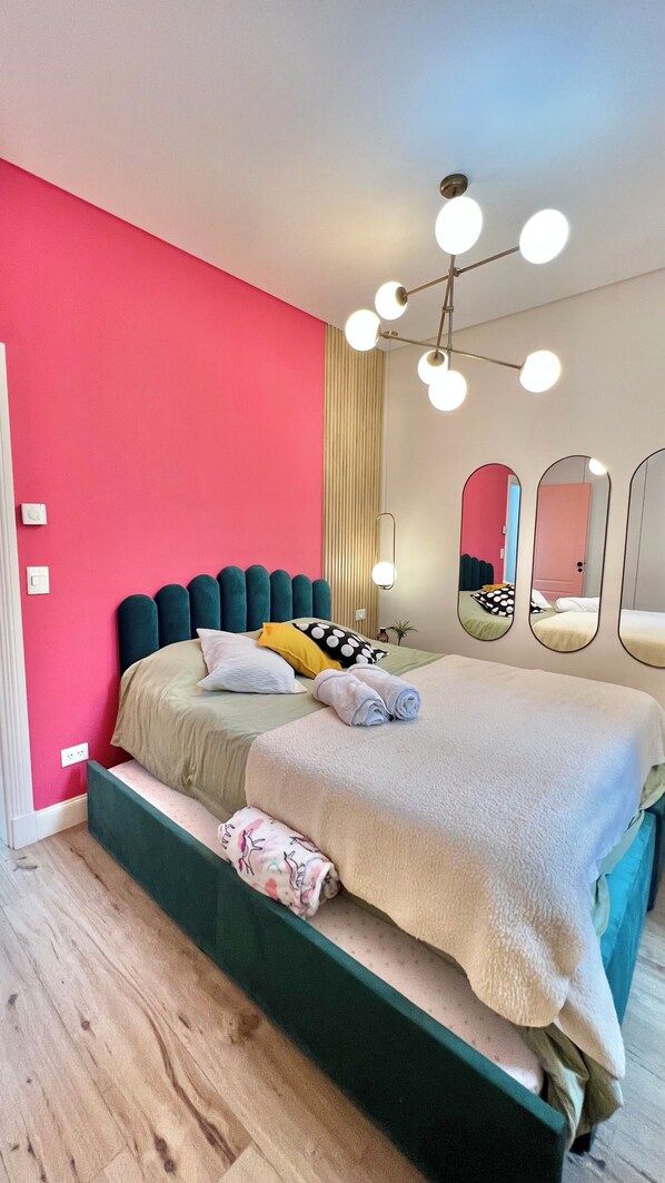 Un dormitorio moderno con cama, mesita de noche, espejo e iluminación en el techo.