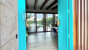 A modern interior with a wooden floor, teal walls, and a dining area with chairs and a table.