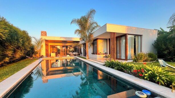 A modern house with a swimming pool, outdoor seating, and lush landscaping.