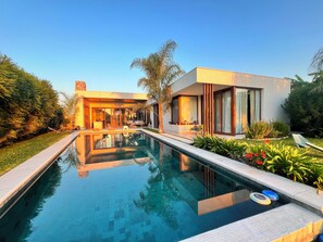 Una casa moderna con piscina, mobiliario exterior y jardines exuberantes.