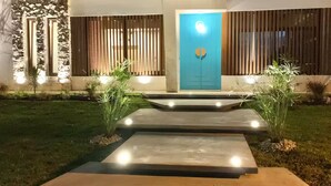 A modern house with a blue door, stone wall, and a well-lit pathway.
