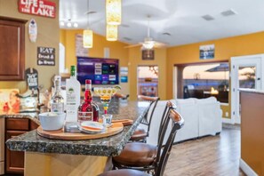 Eine Bar mit einer Granit-Arbeitsplatte, Barhocker und einer Auswahl an Flaschen und Gläsern.