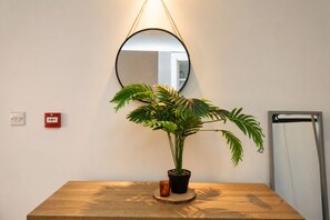 Ein Holztisch mit einem Blumentopf, einem runden Spiegel und einem Rauchmelder an der Wand.