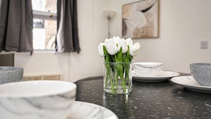 Une cuisine dotée d’un plan de travail en marbre, d’un vase en verre contenant des tulipes blanches et d’un tableau accroché au mur.