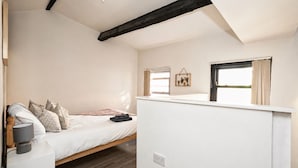 Une chambre à coucher avec un lit, une table de chevet, une lampe et une fenêtre avec des rideaux.