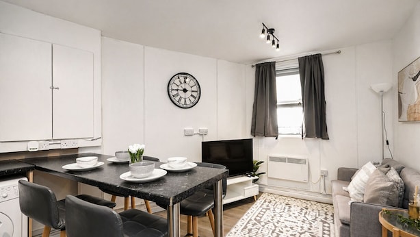 Une cuisine moderne avec un coin repas, un téléviseur à écran plat et un salon comprenant un canapé et une table basse.