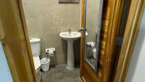Un bany amb un lavabo de pedestal, vàter i paperera.
