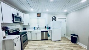 A modern kitchen with white cabinetry, stainless steel appliances, and a wooden floor.