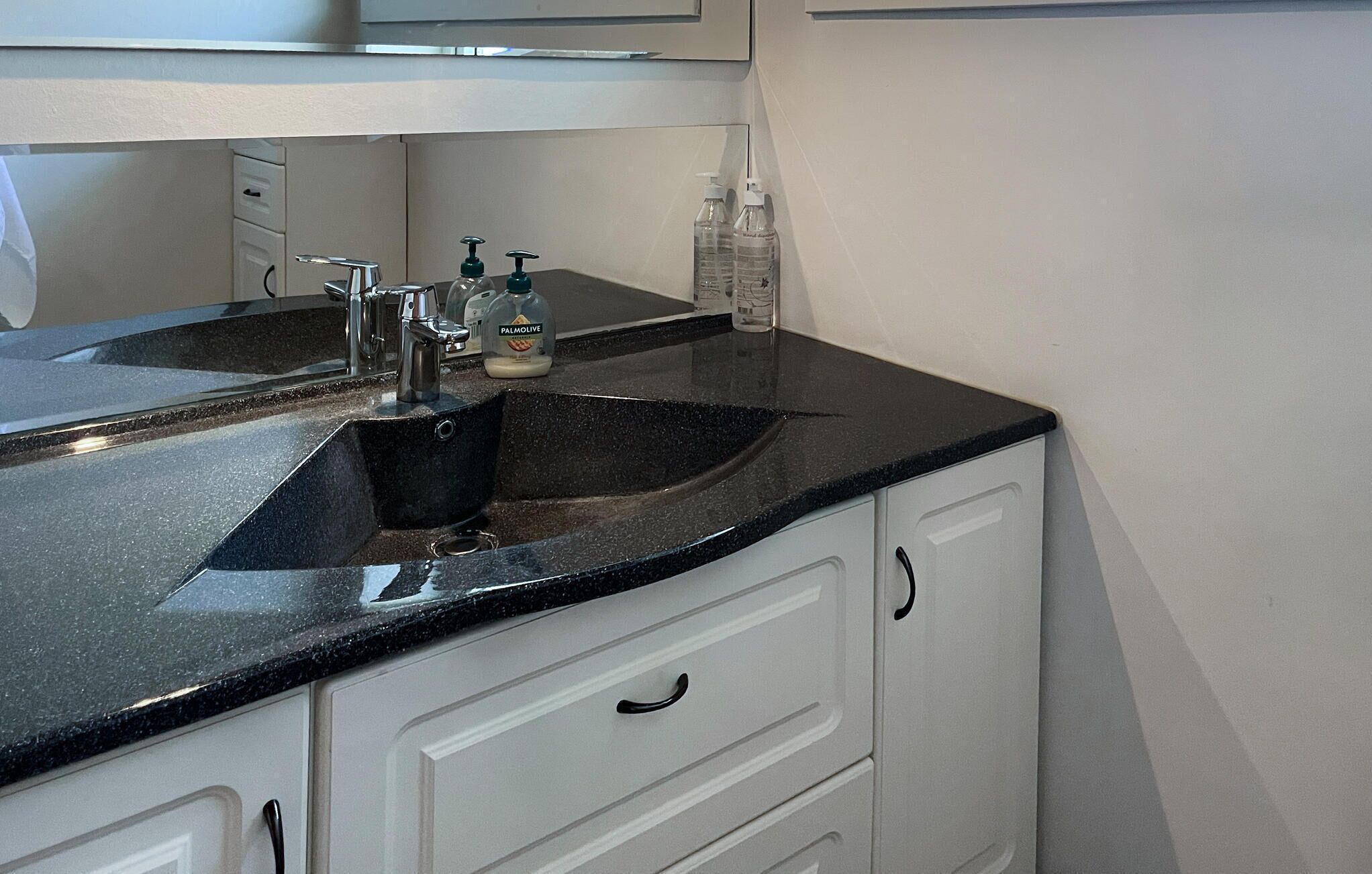 Une salle de bain avec un double vasque, des meubles blancs et un miroir au-dessus de la vasque.