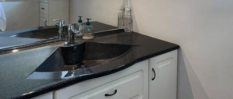 Une salle de bain avec un double vasque, des meubles blancs et un miroir au-dessus de la vasque.