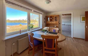 A room with a table and chairs, a view of a lake, a wooden cabinet, and a kitchen area. - Awesome home in Hobro with WiFi (Hobro)