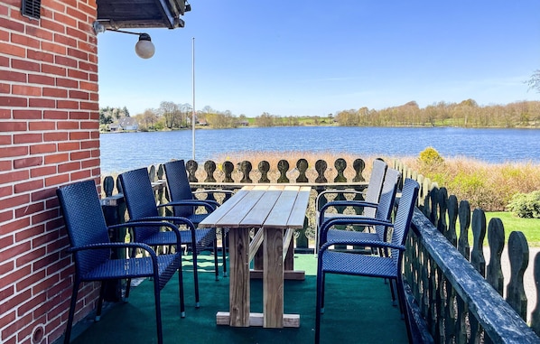 A patio with a table and chairs, a brick wall, and a view of a lake. - Awesome home in Hobro with WiFi (Hobro)