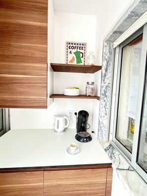 Eine Küche mit einer Kaffeemaschine, einem Wasserkocher und einer Kaffeetasse auf der Arbeitsfläche.