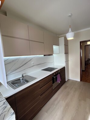 Eine moderne Küche mit Marmorarbeitsplatte, eingebautem Ofen und Holzausbau.