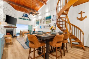 A dining area with a wooden table, chairs, and a view of the ocean. - Oceanfront Condo | Rooftop Terrace | Arcades | (Indian Shores)