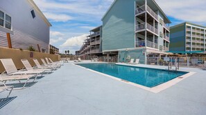 A pool area with lounge chairs, a swimming pool, and multi-story buildings with balconies. - Steps to the Sand: Romar Beach 106 (Orange Beach)