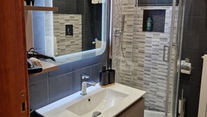 A modern bathroom with a large mirror, a sink, a shower enclosure, and a toilet. - Between Sea and Villages: your Refuge in Pogli (Pogli)