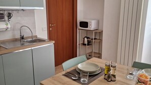 A compact kitchen with a sink, microwave, and a flat-screen TV mounted on the wall. - Between Sea and Villages: your Refuge in Pogli (Pogli)