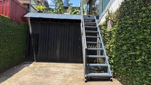A gated entrance with a metal ladder leading up to a building, surrounded by greenery. - Volcano View (San Carlos)