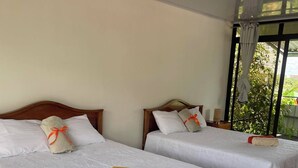 Two beds with white linens and pillows, wooden headboards, and a view of greenery outside. - Volcano View (San Carlos)