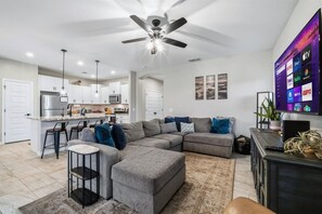 Een moderne woonkamer met een modulaire bank, een salontafel en een televisie waarop streamingdiensten worden afgespeeld.