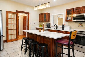 A kitchen with a large island, wooden cabinets, a refrigerator, and a microwave. - The Artful Retreat Close to Gillette Stadium  (Boston)