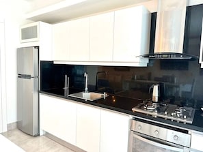 Eine moderne Küche mit weißen Schränken, einem Edelstahl-Kühlschrank, einem Gasherd und einem eingebauten Backofen.