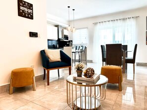 Ein modernes Wohnzimmer mit einer Couch, einem Hocker und einem Couchtisch mit Büchern und Dekoration.