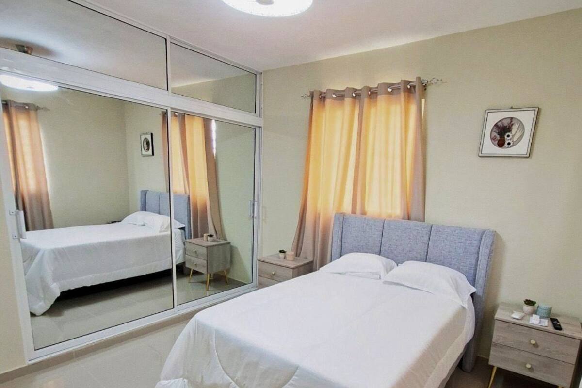 A bedroom with a bed, a nightstand, a mirror, and a ceiling fan.