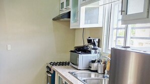 A kitchen with a stove, microwave, blender, and stainless steel refrigerator. - MB apartment  (Azua)