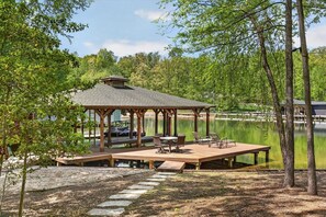 A wooden gazebo with a roof, surrounded by a deck, near a body of water. - Waterfront Log Cabin with Boathouse, sandy beach and firepit on Lake Anna (Bumpass)