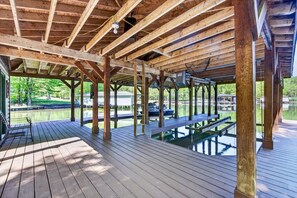 A wooden deck with a pool, benches, and a view of a lake. - Waterfront Log Cabin with Boathouse, sandy beach and firepit on Lake Anna (Bumpass)