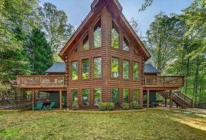 A log cabin with a central tower, a deck, and a staircase. - Waterfront Log Cabin with Boathouse, sandy beach and firepit on Lake Anna (Bumpass)