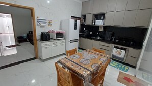 A compact kitchen with a dining area, white cabinets, a microwave, a refrigerator, and a stove. - Charming house near the state hospital, bakery, supermarket, and pharmacy. (franca)