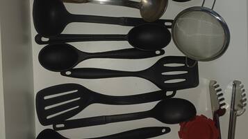 Uma gaveta com diversos utensílios de cozinha, incluindo espátulas, colheres, um escorredor e uma faca.
