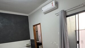 A bedroom with a bed, an air conditioning unit, a sliding glass door, and a wooden floor. - Charming house near the state hospital, bakery, supermarket, and pharmacy. (franca)