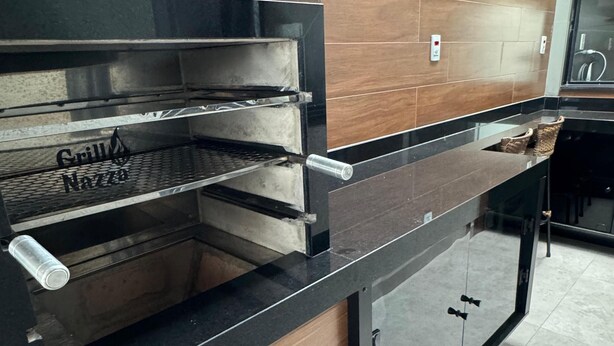 A kitchen with a built-in grill, wooden cabinets, and a stainless steel countertop. - Charming house near the state hospital, bakery, supermarket, and pharmacy. (franca)